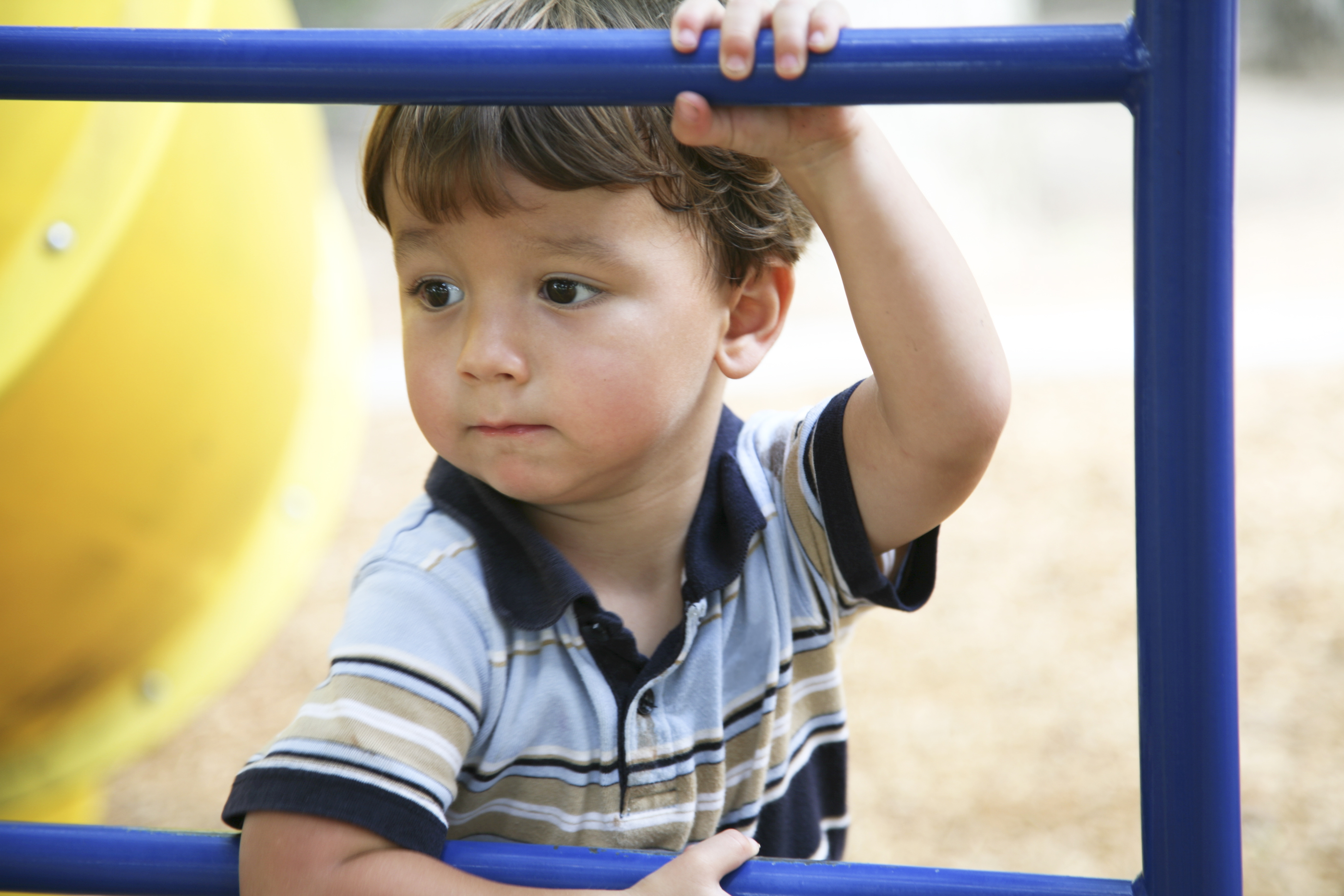 Concerned Young Boy Holding On to Bar at a Playground.